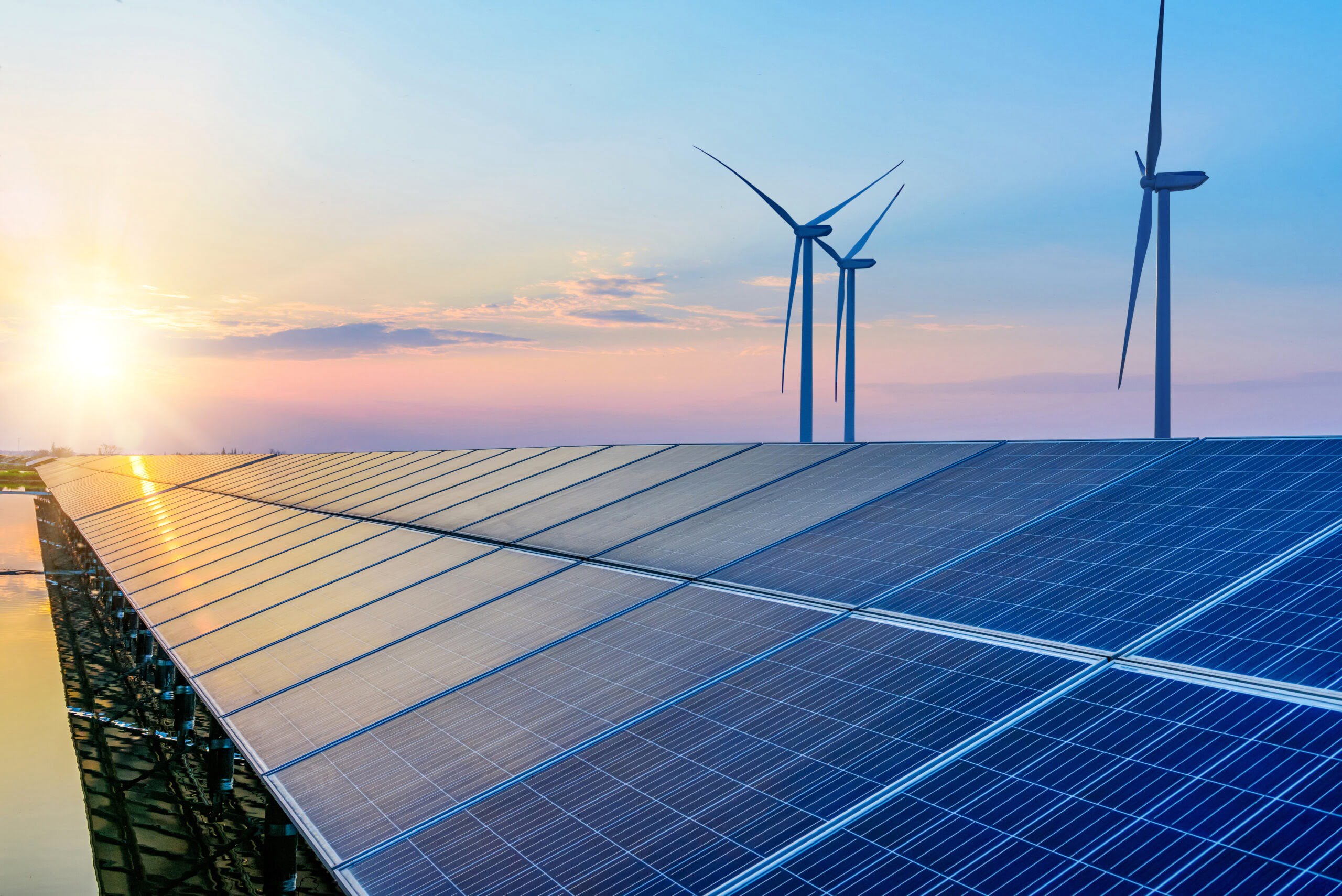 Solar panels and wind turbines at sunset