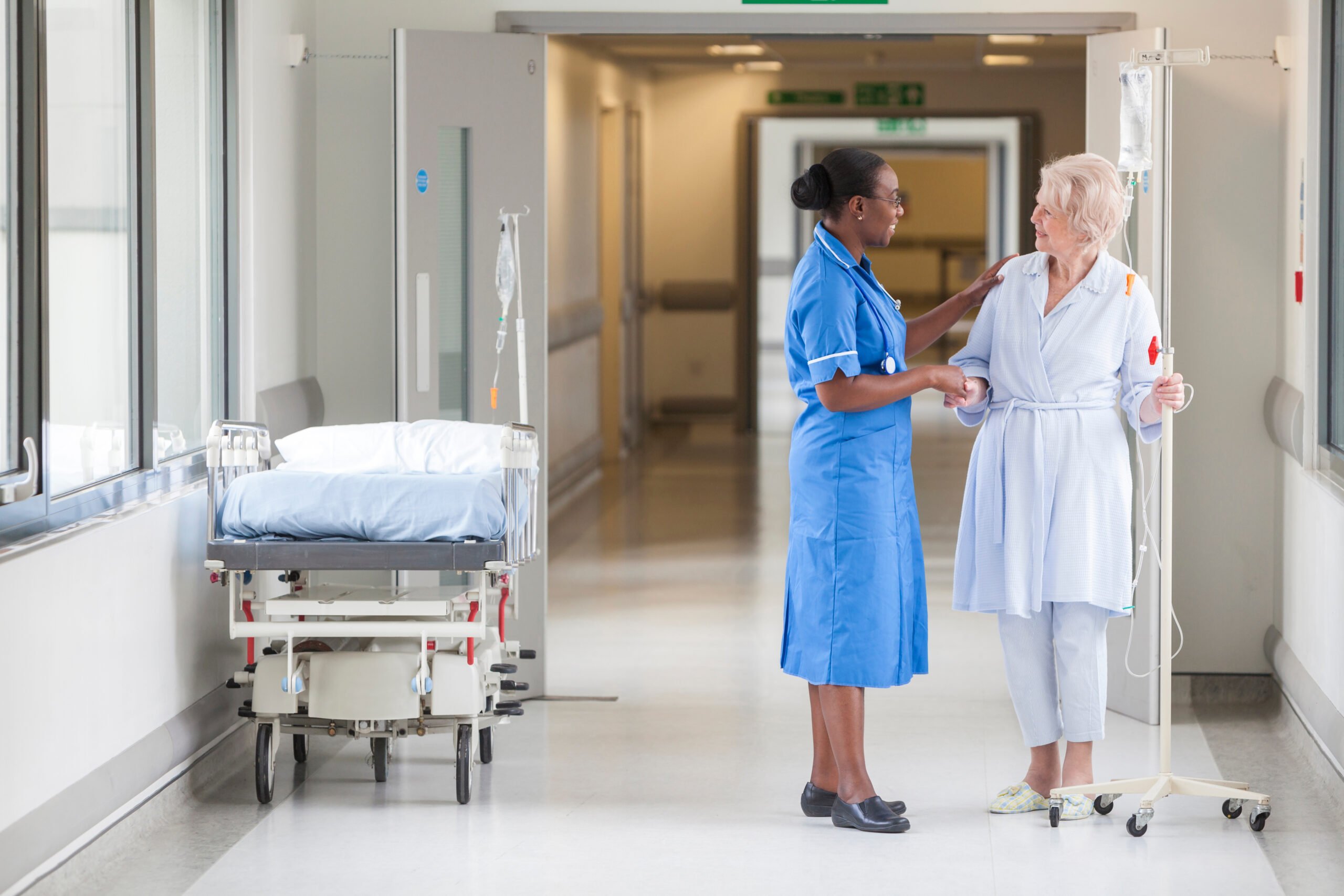 Senior,Female,Woman,Patient,In,Hospital,Corridor,With,African,American