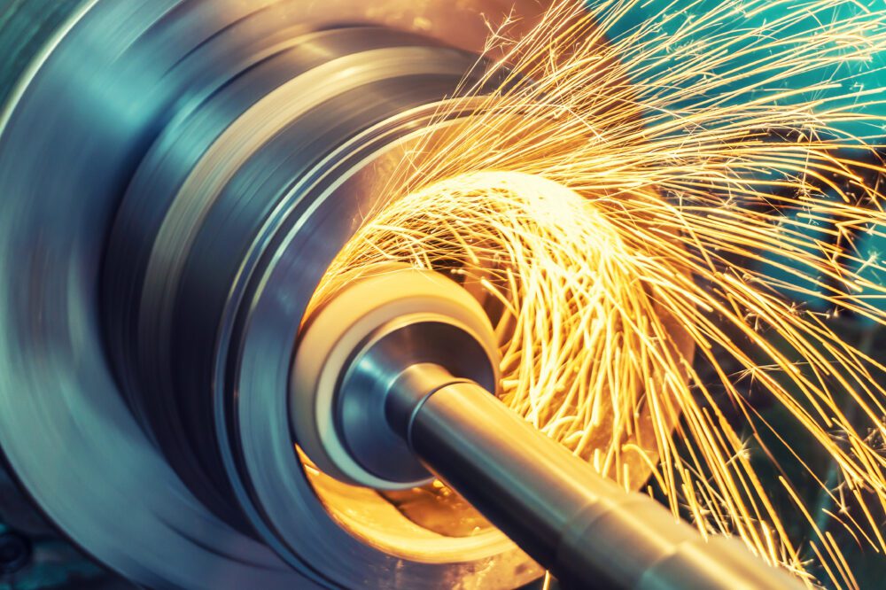 Grinding of a cylindrical part with an abrasive wheel on a machine, sparks fly in different directions.