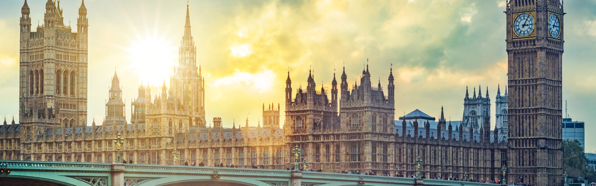 Houses of Parliament and Big Ben against a burst of sunlight from behind clouds.