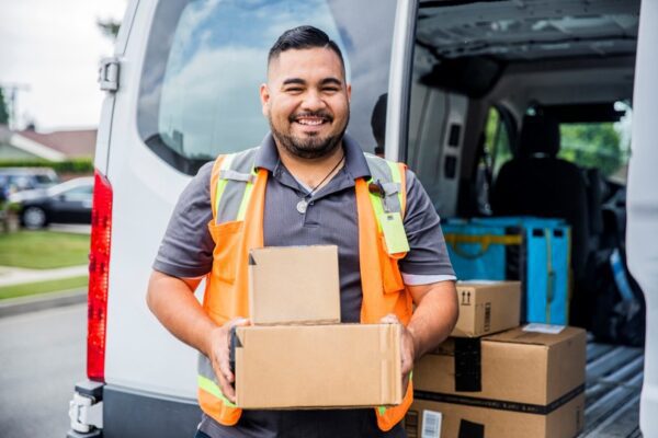 Image for Man holding boxes in front of a van