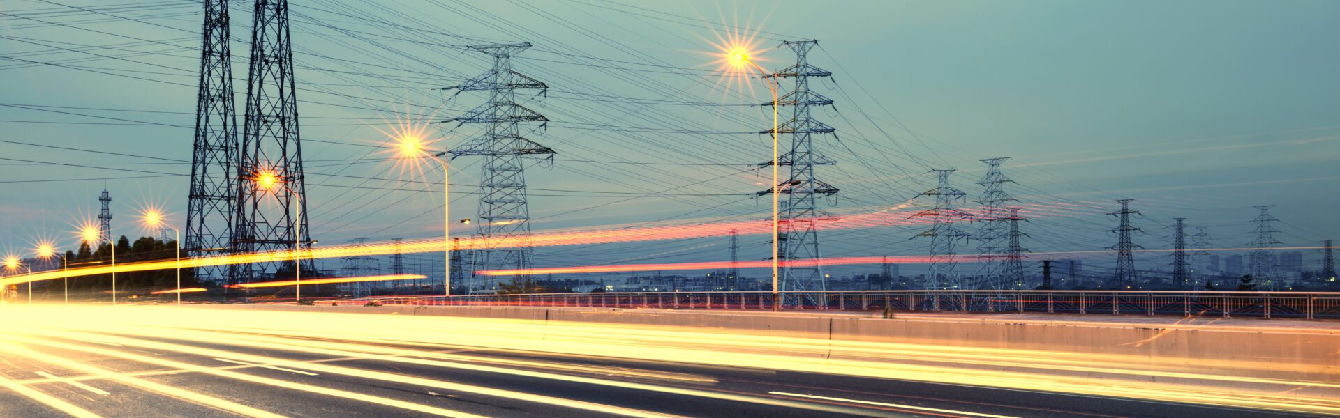 Electricity pylons near a road at twilight.