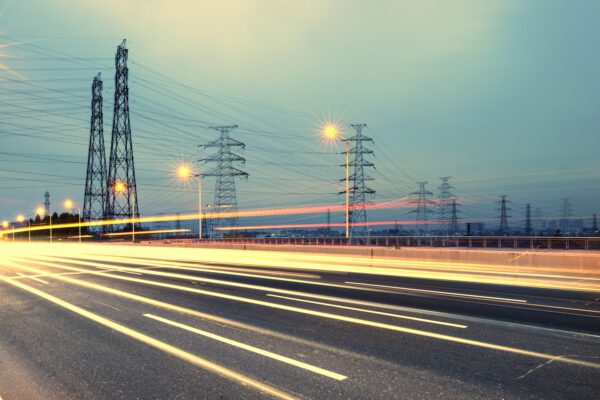 Feature image Electricity pylons near a road at twilight.