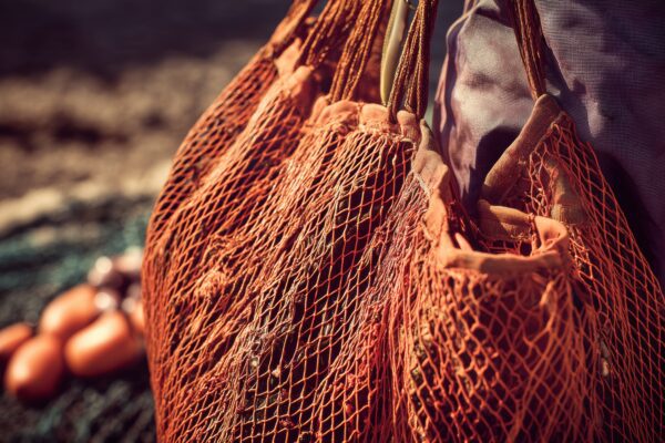 Close up of orange netting bag with food waste and soil in the background