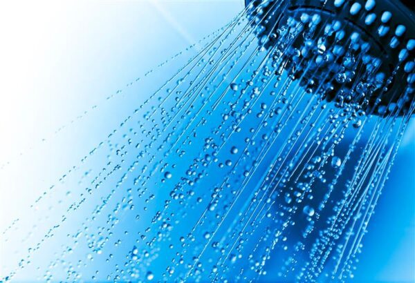 Shower head against blue background. (Source: AdobeStock)