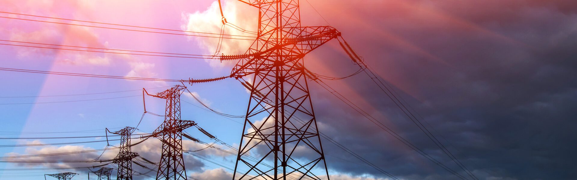 Pylons under a cloudy sky with sunlight breaking through