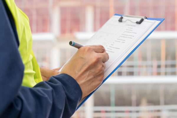Image for Hands, engineer and clipboard in city for checklist, inspection notes or safety compliance. Person, writing with documents for urban development, project management or supervisor paperwork and pen